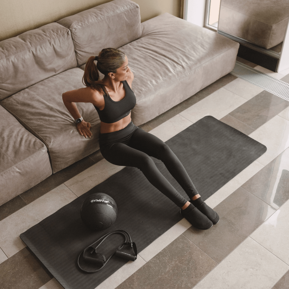 Woman doing tricep dips on a yoga mat wearing Gympak Base Socks during a home workout